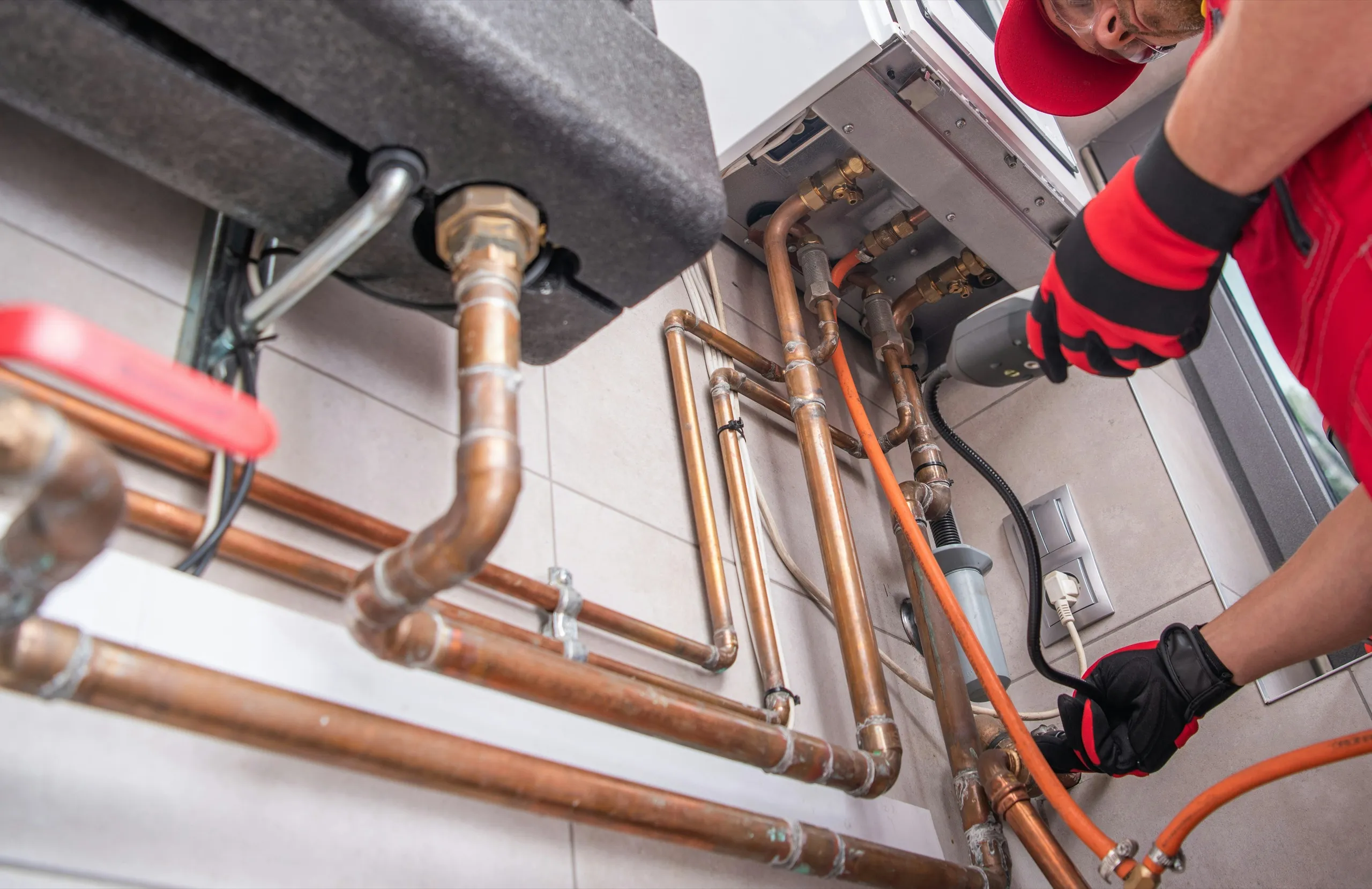 Installateur verlegt Kupferleitungen an einer Heizungsanlage